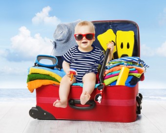 Baby in Travel Suitcase. Kid inside Luggage Packed for Vacation Full of Clothes, Child and Family Trip