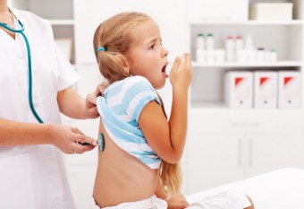 Little girl coughing at the doctor checkup - a health professional consulting her
